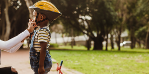 Mom helps her son put on a helmet so he can ride his bike safely